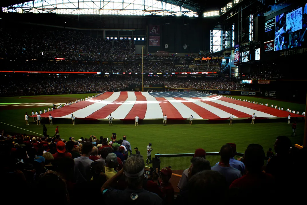 a large American flag is displayed on a baseball field