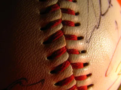 Players&rsquo; signatures are blurred as the red threading of this baseball comes into focus.

