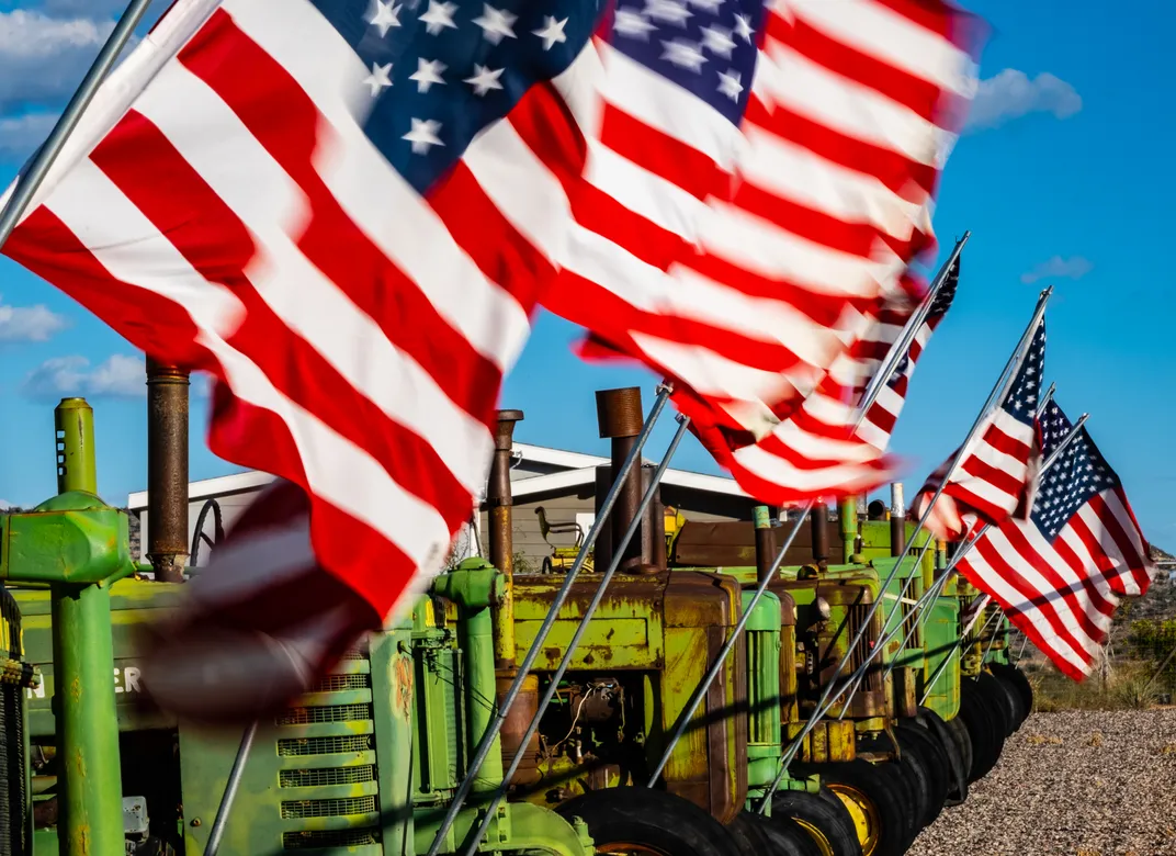 American flags fly on top of green tractors