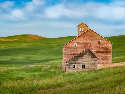 The asymmetrical angles of the roof of this old, abandoned barn complement the scenic rolling hills surrounding it.