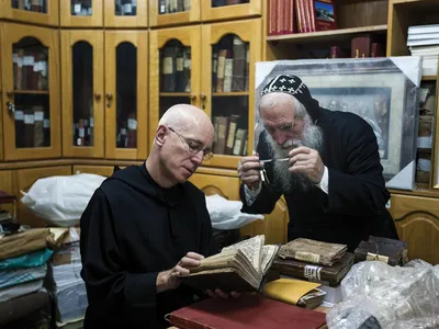 At the library of St. Mark’s Syrian Orthodox Monastery in Jerusalem, Stewart and Abouna Shimon Can, a monk, view centuries-old Syriac manuscripts.